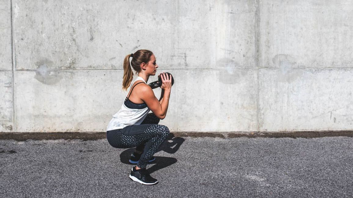 Woman doing squats with a kettlebell